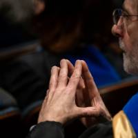 Faculty member sitting with fingertips together watching the program